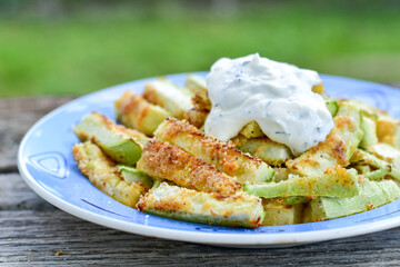 Home made keto   organic fried zucchini sticks with parmesan cheese and almond flour   and garlic yogurt sauce on wooden background. Ketogenic diet food