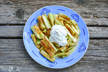 Home made keto   organic fried zucchini sticks with parmesan cheese and almond flour   and garlic yogurt sauce on wooden background. Ketogenic diet food