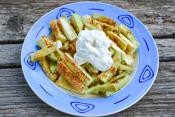 Home made keto   organic fried zucchini sticks with parmesan cheese and almond flour   and garlic yogurt sauce on wooden background. Ketogenic diet food