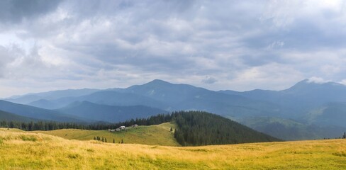 View of hut and summits on the slope of the forest-covered mountains in the Swiss Alps under dramatic clouds on rainy day