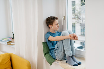 Thoughtful young boy sitting listening to music