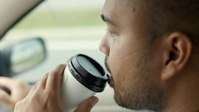 Young asian man driver was drowsy. He yawned and was about to fall asleep. doze off Driving for a long time, sleep deprivation. He drinking hot coffee drink coffee to wake up and drive carefully.