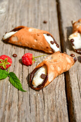  Sicilian cannoli . Тypical  italian   home made dessert with ricotta cheese, chocolate and raspberryes on wooden background