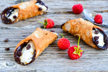  Sicilian cannoli . Тypical  italian   home made dessert with ricotta cheese, chocolate and raspberryes on wooden background