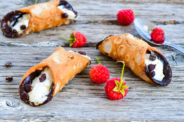  Sicilian cannoli . Тypical  italian   home made dessert with ricotta cheese, chocolate and raspberryes on wooden background