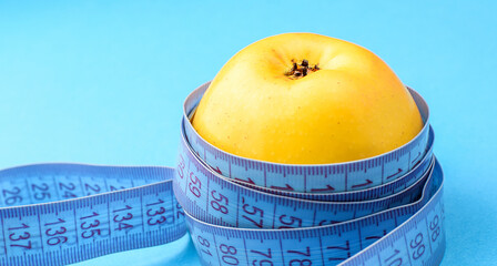 Yellow apple wrapped in a centimeter tape on a colored background. Healthy food, calorie content....