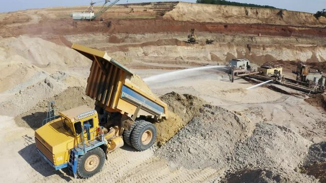 Haul Trucks conceal ground on open coal quarry. Dump Trucks. A heavy dump truck unloads sand. Large dump trucks unload sand in the quarry