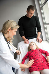 Fototapeta premium Father with girl being examined by female pediatrician in clinic