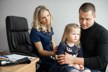 Father with girl being examined by female pediatrician in clinic