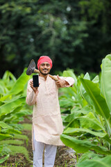 Indian farmer showing smartphone screen at banana agriculture field.