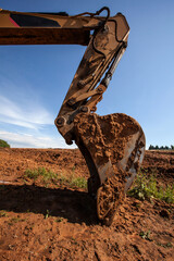 heavy yellow excavator with shovel standing during earthmoving works outdoors at construction site