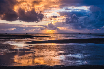 Sunset on a cloudy colorful sky over the North Sea in Denmark with high reflection in the water