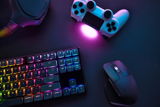 Top down view of various gaming accessories laying on table. Colorful illuminated devices.