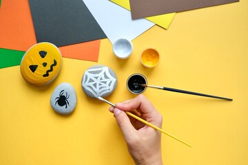 ow to draw a pumpkin with paints on a stone for the Halloween holiday. The DIY concept. Children's creativity. Step by step. 