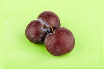 Obraz premium Two ripe juicy plums on a green background.