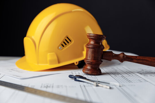 Wooden gavel with yellow helmet. Construction law concept