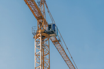 Yellow tower construction crane against blue sky background