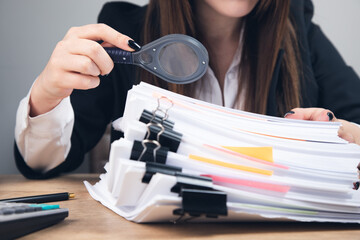 woman holding magnifying glass and documents