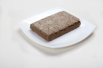 Sunflower seed halva lies on a white porcelain plate on a white background.