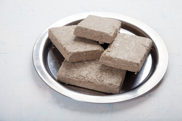 Halva from sunflower seeds in briquettes in a metal plate stands on a white background.