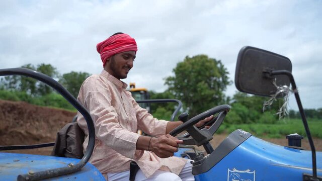 Indian farmer working with tractor at farm.