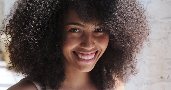 Headshot of a gorgeous brunette young afro-American lady with fizzy hairstyle smiling joyfully and flashing her white teeth to the camera on her first day off.