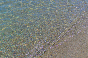 Transparent sea wave on the sandy shore.
