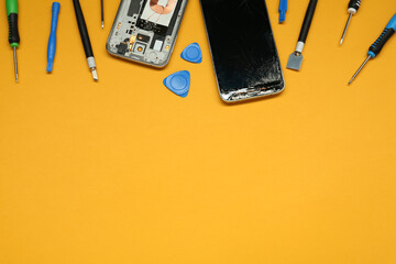 Damaged smartphone and repair tool set on orange background, flat lay. Space for text