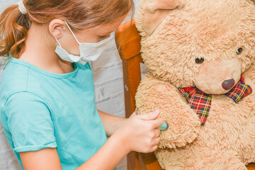 the child girl with a syringe makes an injection vaccination toy bear photo without processing