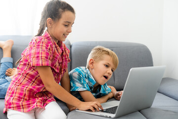 Young boy with a laptop computer sitting near a girl