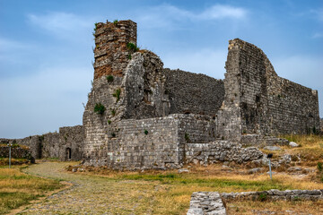 Fototapeta na wymiar Ruins of a medieval building in Shkoder Castle (Albania). Dilapidated ancient stone walls against the blue sky