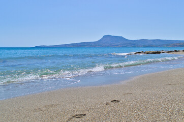 Sea waves on the sandy shore overlooking the distant stone mountains.