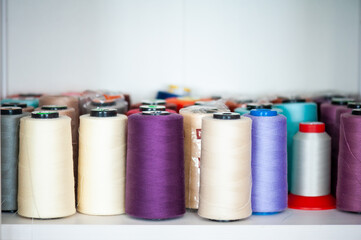 Sewing factory concept. Spools of thread and basic sewing tools including pins, needle, a thimble, and tape measure.
