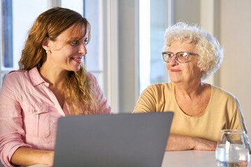 Junge Frau und Senior Mutter zusammen am Tisch mit Laptop