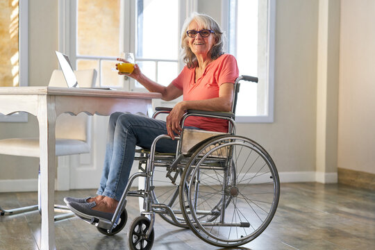 Seniorin im Rollstuhl nach Schlaganfall trinkt Orangensaft