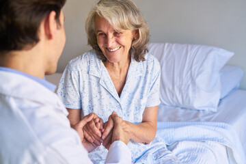 Altenpfleger hält die Hände einer Seniorin als Trost