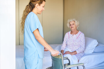 Obraz premium Pflegehilfe bringt Rollstuhl ans Bett einer behinderten Seniorin