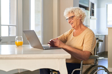 Glückliche Seniorin im Rollstuhl beim Video Call mit Laptop PC