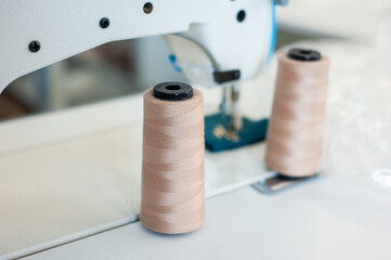 Fashion Design Studio. Hanging Clothes, Sewing Machine and Various Sewing Related Items on the Table, Mannequins Standing, Colorful Fabrics.