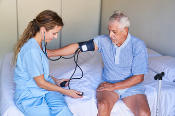 Krankenschwester misst Blutdruck bei einem Senior