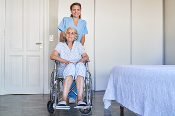 Altenpflegerin schiebt Seniorin nach Schlaganfall im Rollstuhl