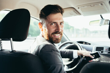 The driver of a man in a business suit looks at the camera