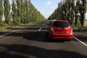 Red car on asphalt road in countryside