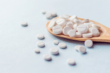 medicine tablets on a wooden spoon isolate on white background