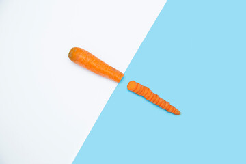 Carrot cut in half on white blue background. Minimal concept. Flat lay. Top view.