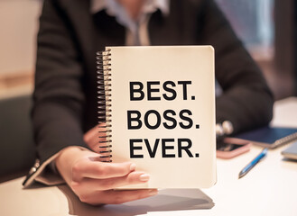 Business woman holds a notebook with the text BEST. BOSS. EVER.