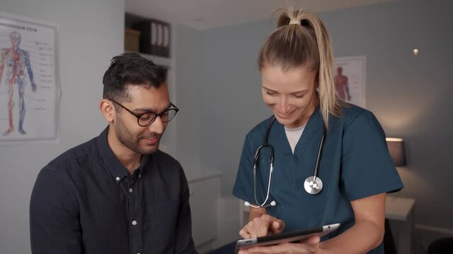 Female doctor assisting patient holding digital tablet