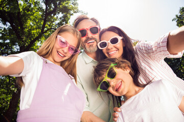 Photo of funny shiny family wear casual clothes dark glasses smiling recording video outdoors urban...
