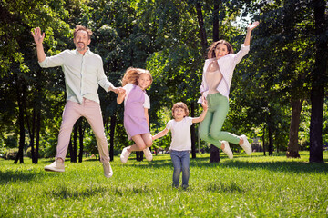 Full length body size view of attractive cheerful adorable carefree family jumping having fun fresh air outdoors