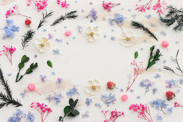Obraz na płótnie Canvas Top view image of pink, white, green and blue flowers composition over white wooden background .Flat lay